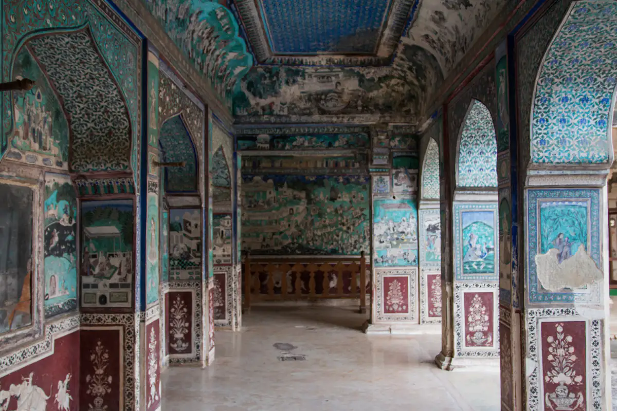 Blue and green murals covering the walls and arches of the Chitrashala in Bundi Palace