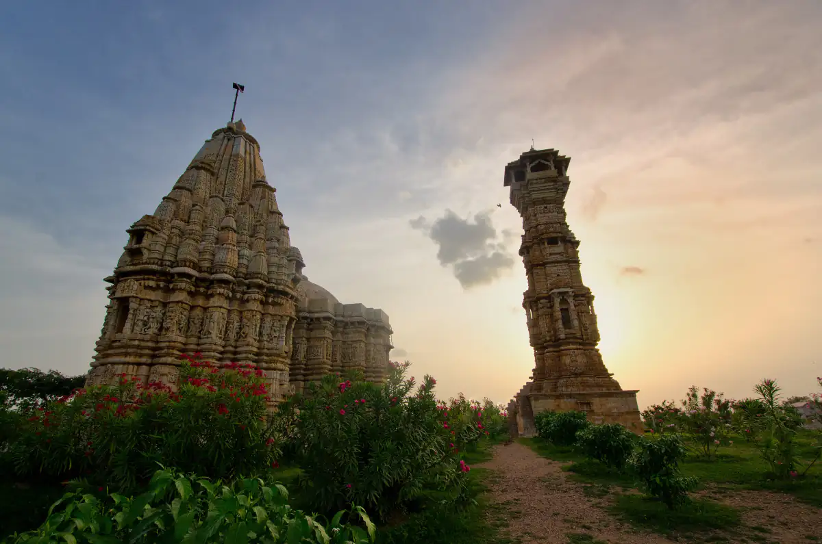 Kirti Stambh, the Jain Tower of Fame, beside a carved temple at Chittorgarh Fort at sunset